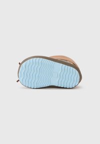 Semelle de chaussure avec une base marron texturée et un motif de bande de roulement en caoutchouc bleu clair. Comprend un petit onglet marron au niveau du talon.