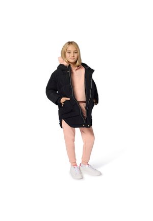 Parka noire rembourrée avec capuche, associée à un sweat à capuche rose et un pantalon de jogging assorti. Des baskets blanches complètent la tenue.
