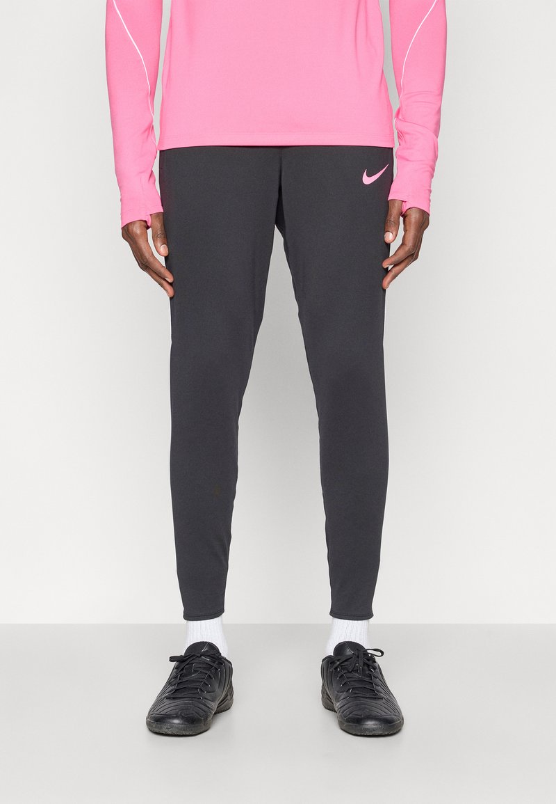 Αθλητικά μαύρα κολάν με στενή γραμμή, που διαθέτουν ένα μικρό ροζ λογότυπο Nike στο αριστερό μηρό. Το υλικό φαίνεται ελαφρύ με ομαλή υφή.