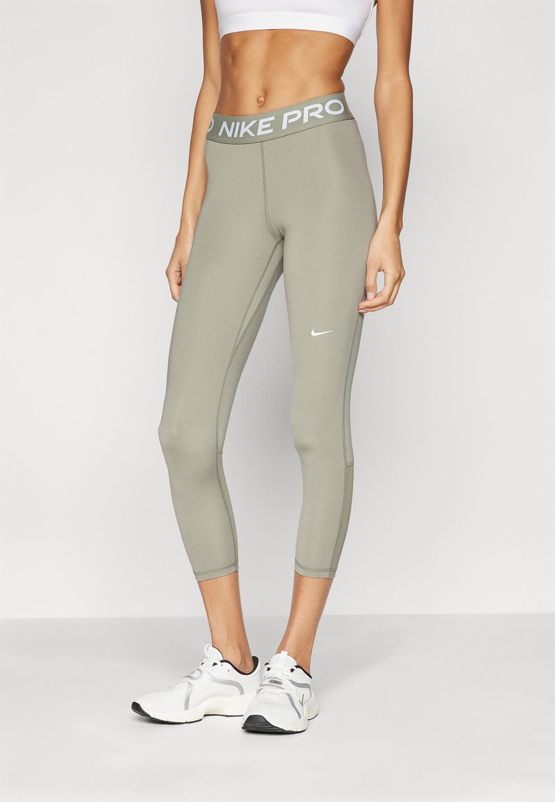 Nike Pro capri tajice u maslinasto zelenoj boji, s širokim pojasom s "NIKE PRO" brendom i bijelim Nike logom na donjem dijelu noge.