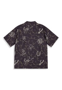 Short-sleeve shirt featuring a dark purple fabric with white whimsical graphics, including animals and lasso patterns, in a loose-fitting design.