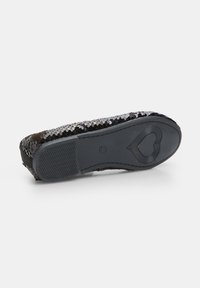 Flat shoe featuring a black sequin upper, rounded toe, and a textured rubber sole with a heart pattern and zigzag tread.