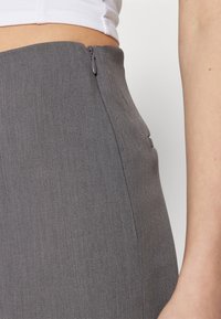 Szara spódnica dopasowana z bocznym zamkiem błyskawicznym i gładką teksturą, o prostym fasonie i ustrukturyzowanej sylwetce.