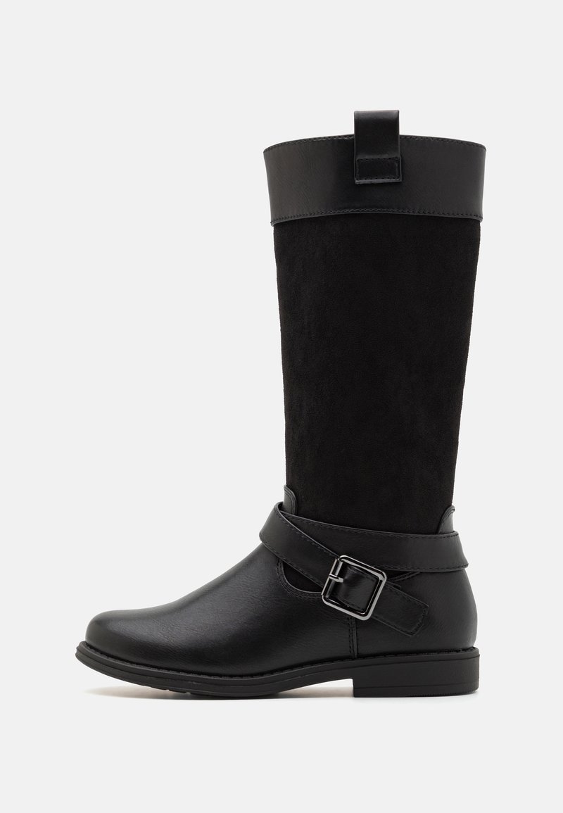 Botte noire mi-mollet avec partie basse en cuir lisse, partie supérieure en daim, sangle décorative à boucle traversant la cheville, et languette de traction en haut.