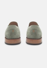 Groene suede schoenen met een afgeronde achterkant, een houten middenzool en een zwarte rubberen buitenzool. Gestikte details zijn zichtbaar op de bovenkant.