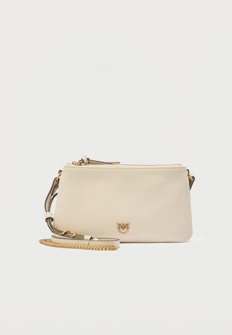 Μπεζ ορθογώνια δερμάτινη τσάντα χιαστή με χρυσή αλυσίδα και μικρό χρυσό έμβλημα στο κέντρο μπροστά.