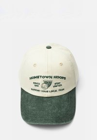 Casquette de baseball à visière verte et couronne crème, brodée avec un graphisme de panier de basket et un texte soutenant les équipes locales depuis 1991.