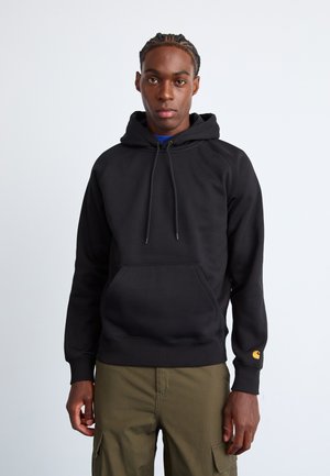 Black hoodie with a kangaroo pocket, drawstring hood, and ribbed cuffs. Notable orange logo on the right sleeve. Cotton-blend fabric.