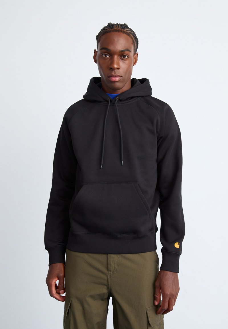 Zwarte hoodie met een kangoeroezak, een trekkoordkap en geribde manchetten. Opvallend oranje logo op de rechtermouw. Katoenmix stof.