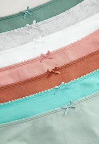 Sept culottes en coton de couleur pastel avec de petits nœuds décoratifs disposés en rangées horizontales qui se chevauchent.