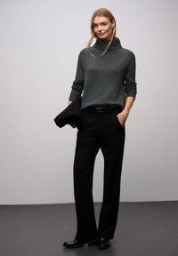 Grå rullekrave-trøje med ribstrikkede manchetter, kombineret med sorte bukser og skinnende sorte sko. Minimalistisk design, glat tekstur og tætsiddende silhuet.