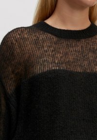 Zwart gebreid sweater met een gestructureerd transparant ontwerp in het bovenste gedeelte en een effen ondergedeelte, compleet met een ronde halslijn.