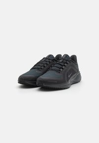Black athletic shoes made of mesh and synthetic materials. Features a textured pattern, padded collar, and rubber sole with traction detailing.