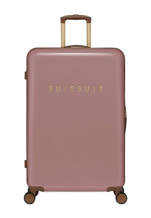 Harde koffer in zacht roze, met een gouden logo aan de voorkant, bruine handgreep en accenten, en vier zwarte wielen voor mobiel gebruik.