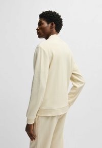 Licht beige sweatshirt met een hoge hals, lange mouwen en geribde manchetten. Zachte textuur en minimalistisch ontwerp zonder zichtbare logo's.
