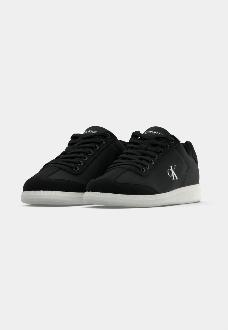 Black fabric sneakers with a white rubber sole, featuring a rounded toe, lace-up design, and a logo on the side and tongue.