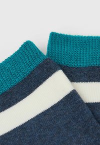 Baumwollsocken mit einem ribbeligen, türkisfarbenen Bündchen, einem dunkelblauen Körper und weißen horizontalen Streifen. Weicher Stoff mit einem klassischen Design.