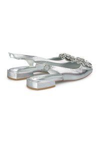Srebrne buty typu slingback z płaskim obcasem, charakteryzujące się metalicznym wykończeniem i dekoracyjnymi ozdobami kwiatowymi w okolicy palców.