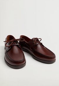 Chaussures en cuir marron à finition lisse, bout rond, design à lacets et détail de bordure cousue. La semelle est plate et légèrement rembourrée.
