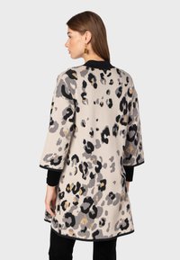 Beige cardigan met luipaardprint, voorzien van zwarte en gouden accenten, met driekwart mouwen en een rechte snit. Glad textiel.