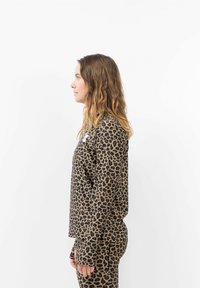 Leopard-Print Langarmbluse aus weichem Stoff, mit einem lässigen Schnitt, überschnittenen Schultern und seitlichen Schlitzen, kombiniert mit passenden Hosen.
