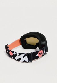 Slidinėjimo akiniai su juodai balta kamufliažo juosta, kurioje yra koralų atspalvių akcentų. Lęšis yra gelsvai tamsintas, o vidus aptrauktas juoda putplasčio pakrove.