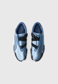 Niebieskie trampki o błyszczącej, teksturowanej powierzchni, wyposażone w dwa czarne paski na rzepy oraz gumową podeszwę z teksturowanym bieżnikiem.