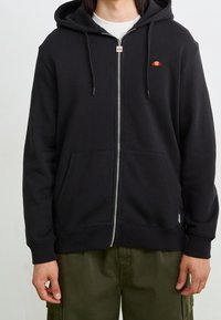 Czarna bluza z kapturem na zamek, wykonana z miękkiego materiału, z przednią kieszenią, ściągaczem przy kapturze i małym wielokolorowym logo na lewej piersi.