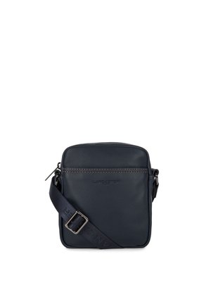 Navy leather crossbody bag with a flat design, zip closure, and adjustable strap. Features brown stitching and a logo on the front.