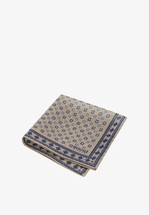 Beige Wolldecke mit einem blauen geometrischen Muster, das zusätzlich Diamant- und Blumenakzente aufweist, gefaltet und mit einem sichtbaren Logo in der unteren Ecke.