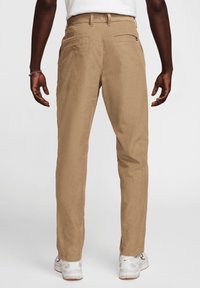 Khaki chinos med rak passform, knäppta bakfickor och en mjuk textur. Bärs med vita sneakers och en enkel vit skjorta.