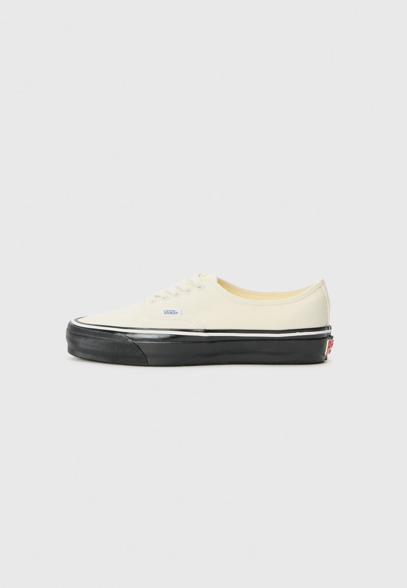 Canvas sneaker in off-white with black rubber sole. Features a low-profile design, rounded toe, and contrasting black outsole accents.