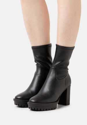 Bottes cheville en cuir noir à finition lisse, design à enfiler, bout arrondi et talon bloc avec une semelle texturée et rainurée.
