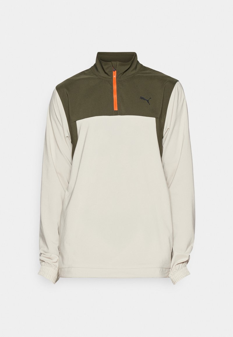 Puma pullover met een beige lichaam en olijfgroene bovenkant, ritskraag met oranje accent, elastische manchetten en zwarte logo-detail.