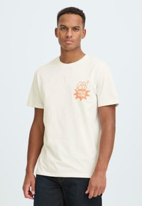 Crème kleurig katoenen T-shirt met een oranje afbeelding aan de voorkant en de tekst "FRESH! BLEND" binnenin een stervorm. Ronde hals en korte mouwen.
