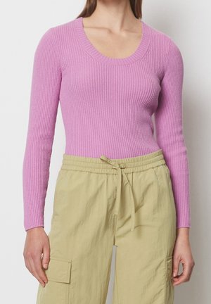 Rippstrickpullover in Hellrosa mit Rundhalsausschnitt und langen Ärmeln, kombiniert mit hellgrünen Cargo-Hosen mit Kordelzugbund.