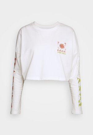 Bijela skraćena dukserica s dugim rukavima. Ima narančaste i zelene grafičke isprintane motive, uključujući cvjetni uzorak i natpis "SURF SOUL."