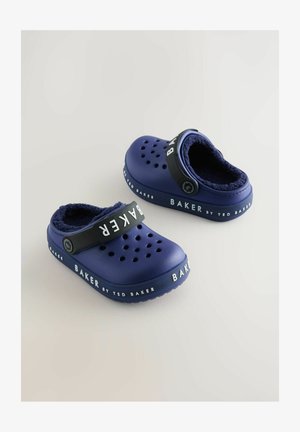 Sötétkék klumpák puha belső béléssel, szellőzőlyukakkal és egy fekete pánttal, amelyen a "BAKER by TED BAKER" márkaneve szerepel.