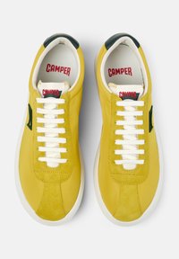 Sneakers in pelle gialla con lacci bianchi, caratterizzati da un accento verde e una finitura testurizzata. Etichetta con il logo visibile sulla linguetta imbottita.