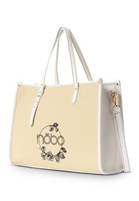 Beige Canvas-Handtasche mit weißen Kunstlederakzenten, ausgestattet mit einem floralen Logodesign und zwei Griffen. Verstellbarer Schultergurt inklusive.