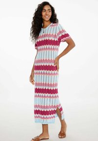 Dzianinowa sukienka midi z wzorem w zygzak w jasnym niebieskim, różowym i burgundowym kolorze, krótki rękaw i boczne rozcięcia dla swobody ruchów.