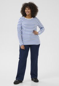 Blue and white striped long-sleeve top, paired with dark blue wide-leg jeans and black platform shoes. Features a round neckline and ribbed fabric.