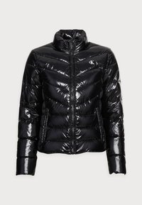 Czarna kurtka puchowa z wysokim kołnierzem, błyszczącym wykończeniem, wzorem w zygzak, pełnym zamkiem z przodu i kieszeniami bocznymi; na piersi znajduje się logo.