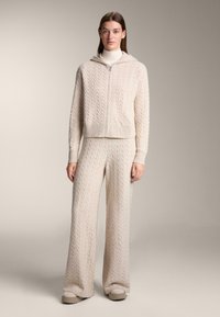 Svetlo béžová pletená súprava na voľný čas s mikinou na zips so vzorom chevron a nohavicami so širokými nohavicami, oboje s rebrovanými manžetami a lemovaním.