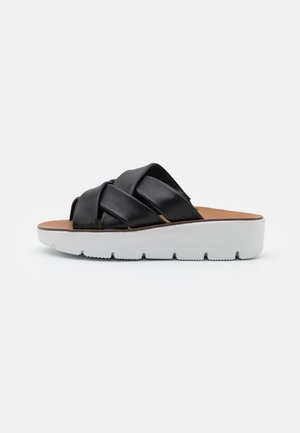 Sort lædersandal med brede krydsede stropper og tyk hvid platformsål.