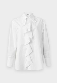 Λευκό μπλουζάκι με μακριά μανίκια, μυτερό γιακά και κεντρική λεπτομέρεια με βολάν που εκτείνεται από τον γιακά μέχρι το κάτω μέρος.