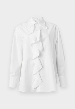 Bílá blůza s dlouhým rukávem, špičatým límcem a středovým volánkem táhnoucím se od límce až po lem.