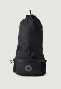 Schwarzer Nylon-Rucksack in zylindrischer Form, mit Kordelzugverschluss, vorderer Reißverschlusstasche und einem Logopatch auf der unteren Vorderseite.