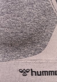 Grijs gestructureerd sportstof met een hexagonaal ontwerp en ribbelaccenten, met een zwart logo gedrukt nabij de onderkant.