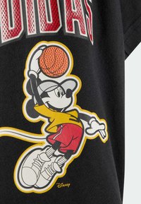 Camiseta negra con un gráfico colorido de un ratón de dibujos animados con ropa deportiva, sosteniendo un balón de baloncesto, con detalles texturizados en el balón.